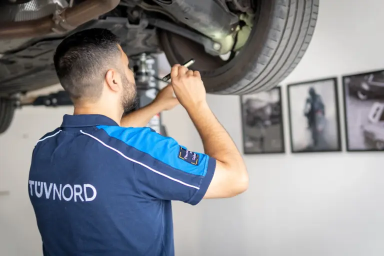 TÜV Prüfer untersucht ein Fahrzeug im Rahmen der gesetzlichen Hauptuntersuchung